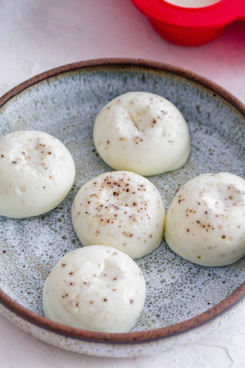 up close image of egg white egg bites on a speckled blue plate. the egg white bites have ground pepper spots on top