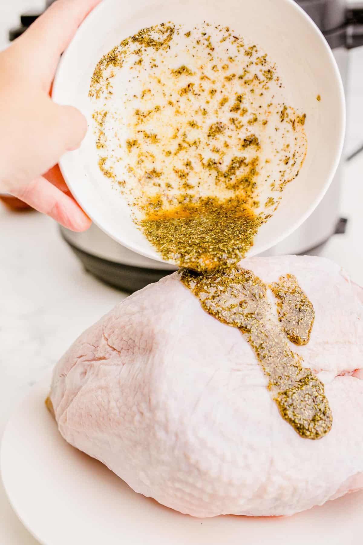 pouring spice mixture on top of turkey breast