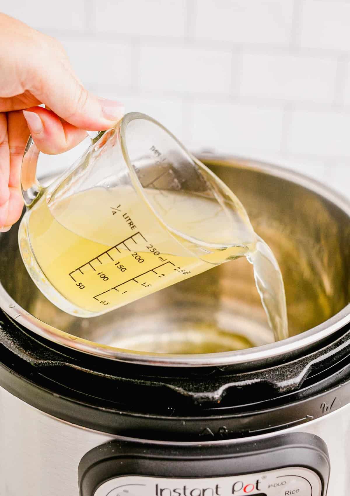 pouring chicken stock into the insert of an instant pot