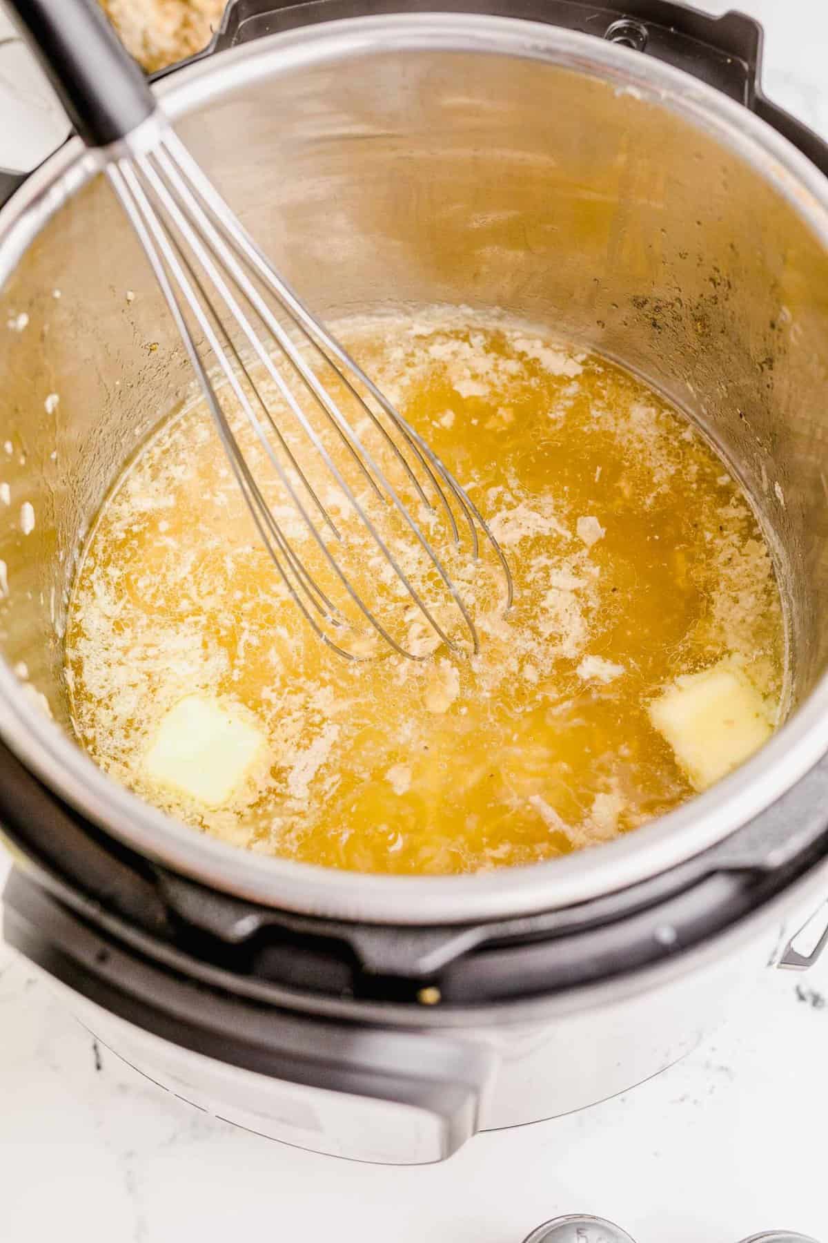 whisking the butter in the insert of the instant pot to melt it