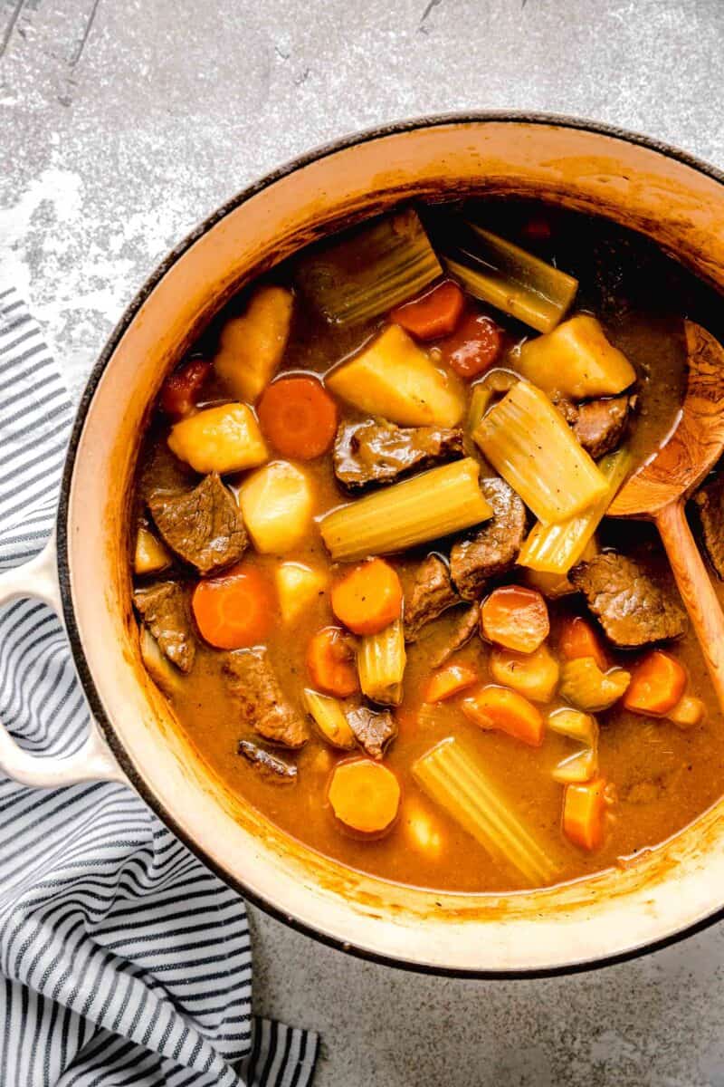 overhead image of japanese curry ingredients in a large dutch oven with a wooden spoon