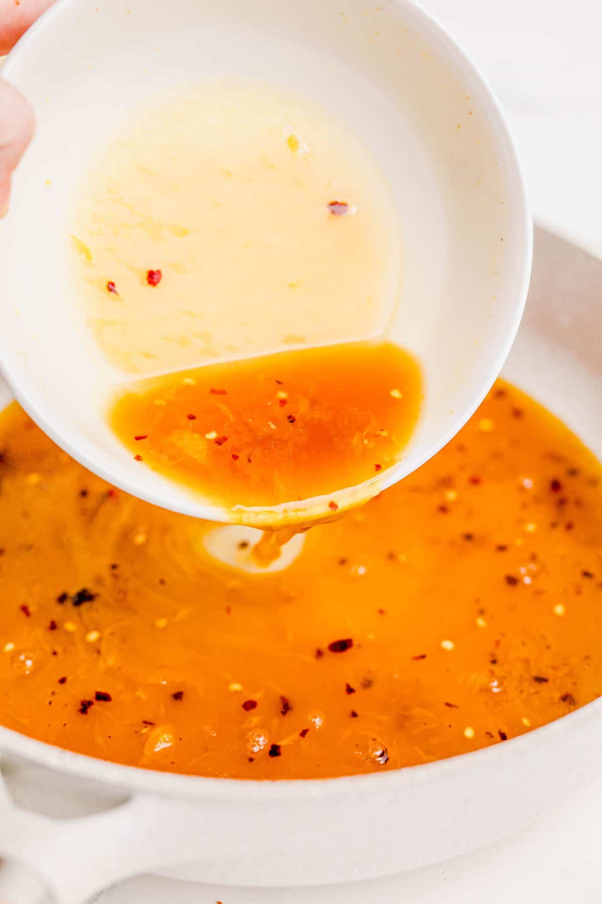 Pouring the orange chicken sauce into the skillet to cook