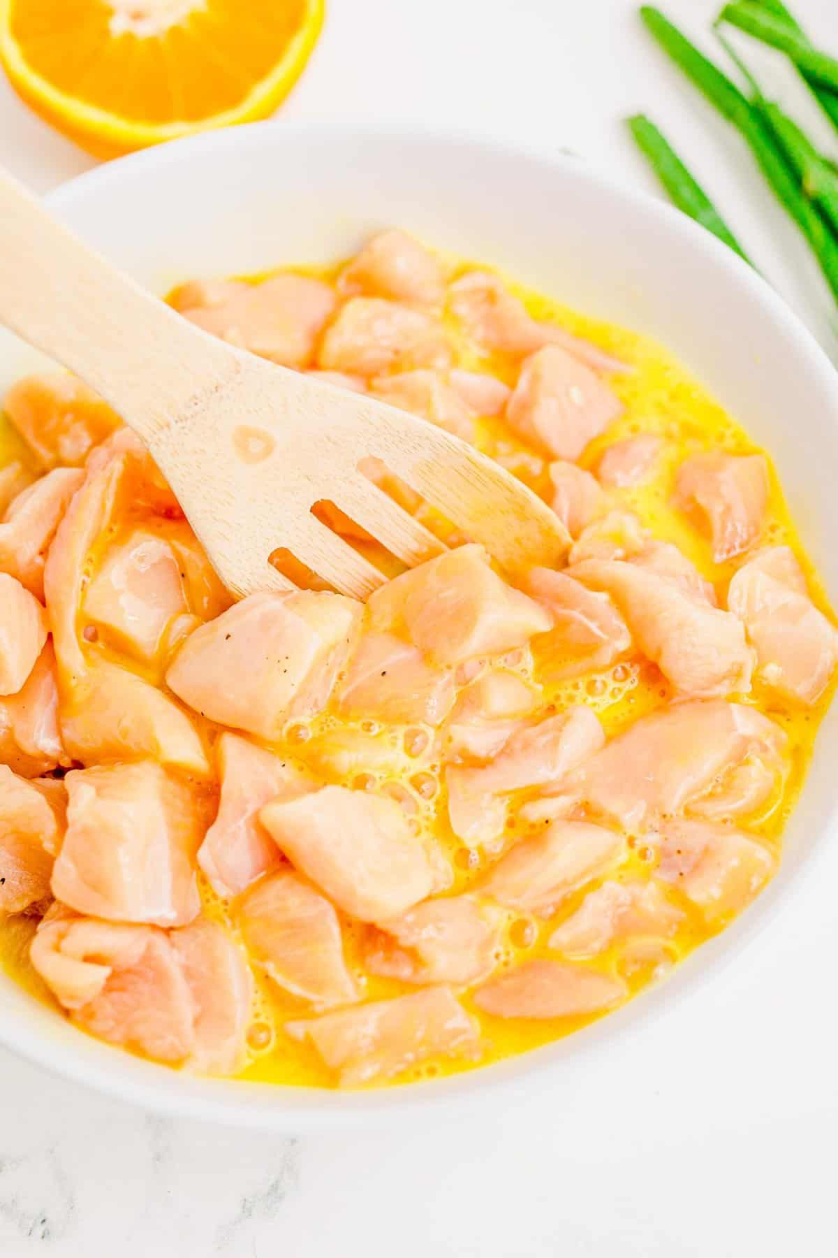 Mixing raw chicken in egg mixture