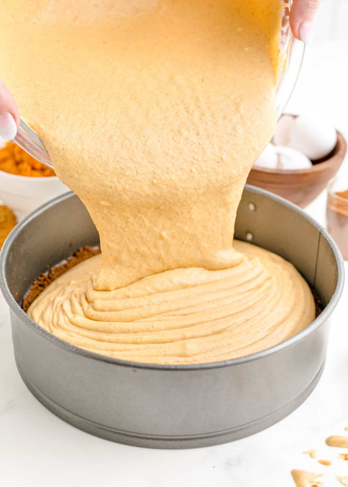 Pumpkin cheesecake batter being poured into a springform pan