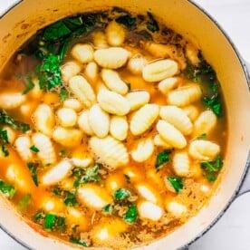 A pot of soup with gnocchi and kale added on top of it