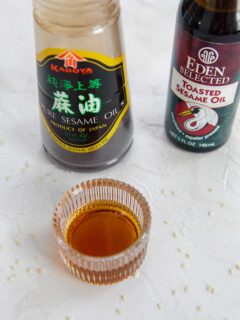 Sesame oil in a glass container with two bottles of sesame oil; one pure and one toasted.