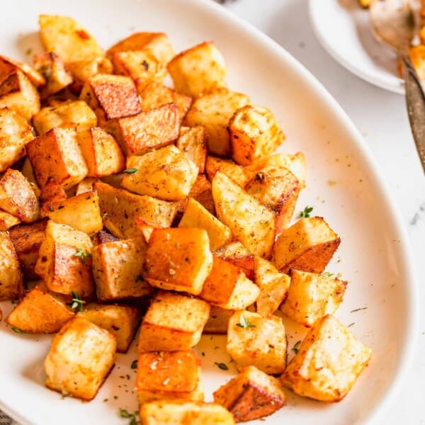 roasted potatoes on a large oval platter with fresh thyme sprinkled on top