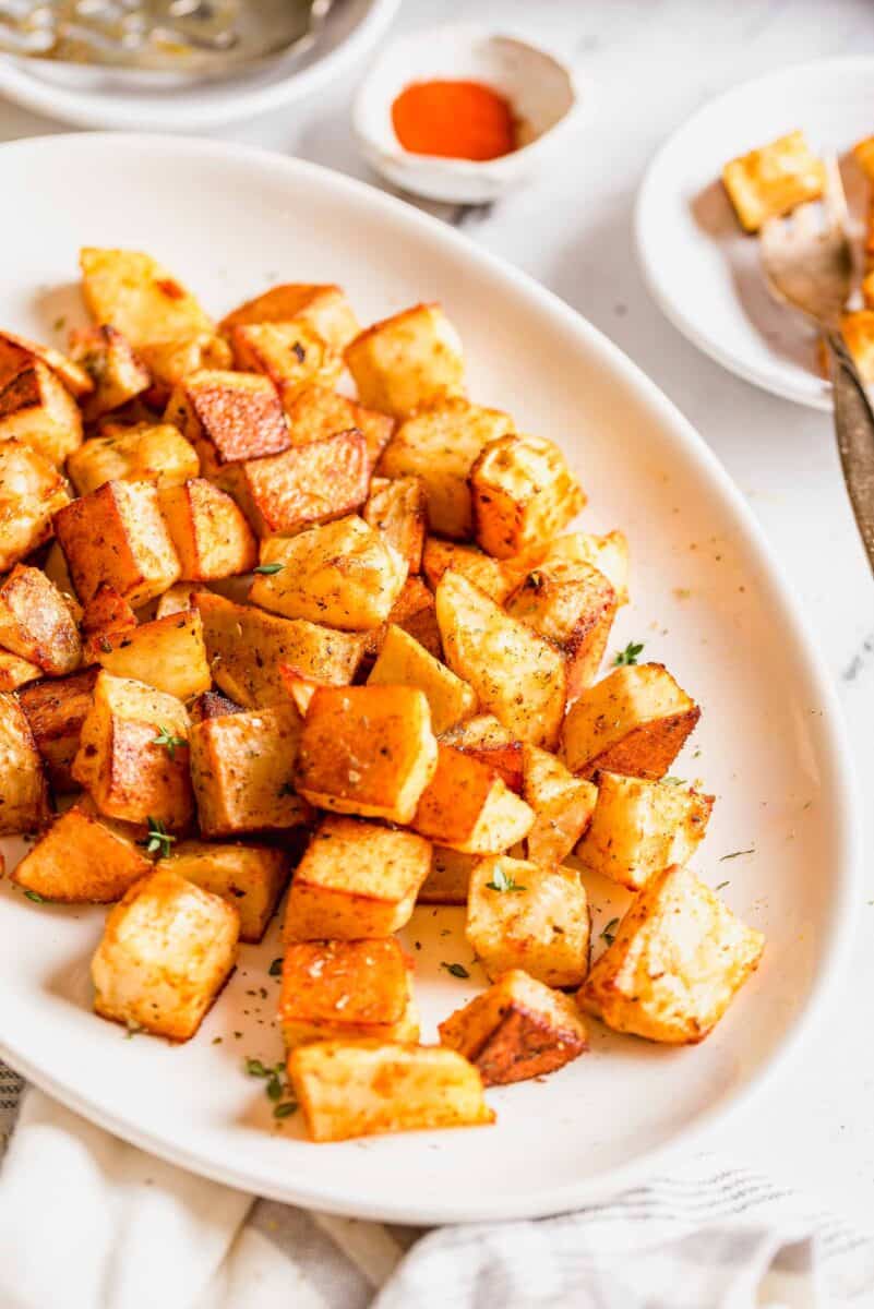 roasted potatoes on a large oval platter with fresh thyme sprinkled on top