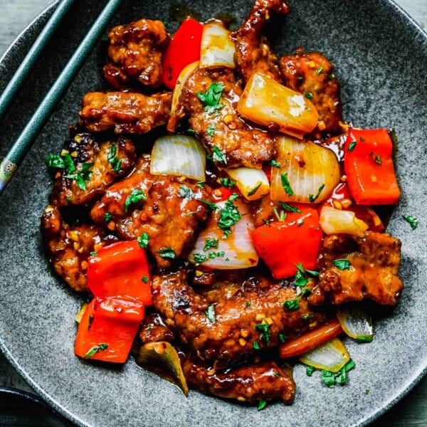 Beijing beef on a plate with chopsticks.