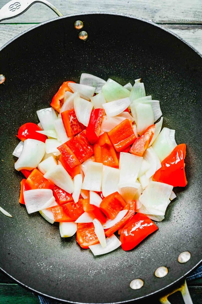 Bell peppers and onions in a wok.