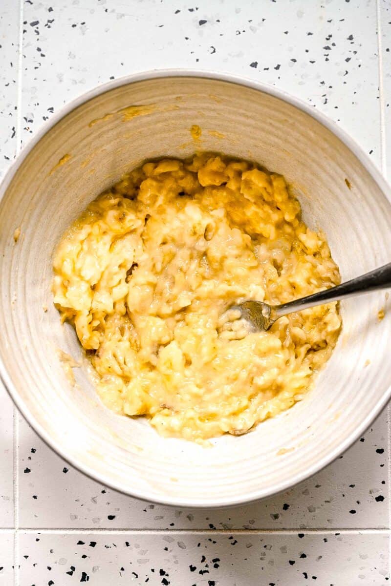 Mashed bananas in a bowl with a fork.