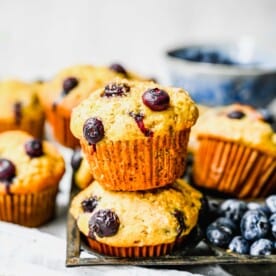 Banana blueberry muffins next to fresh blueberries an a knife.