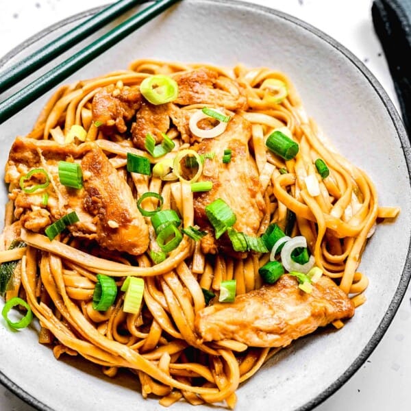 Chicken lo mein served in a bowl with chopsticks.