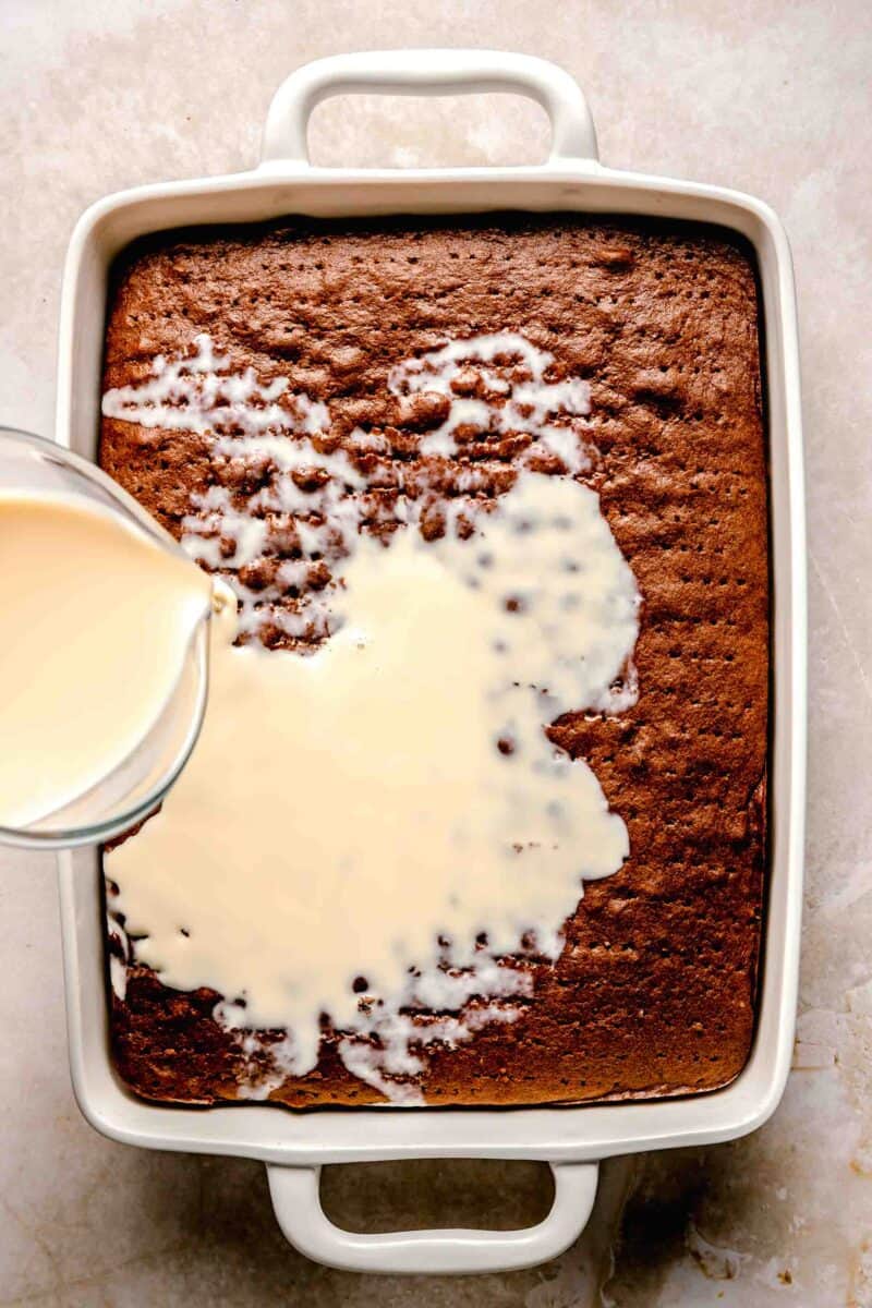 Pouring 3 milk mixture over chocolate tres leches cake.