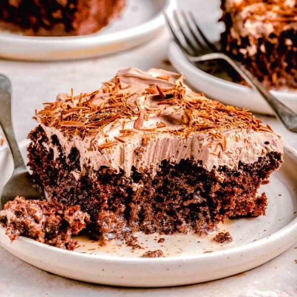 Sliced chocolate tres leches cake on plates with a fork.