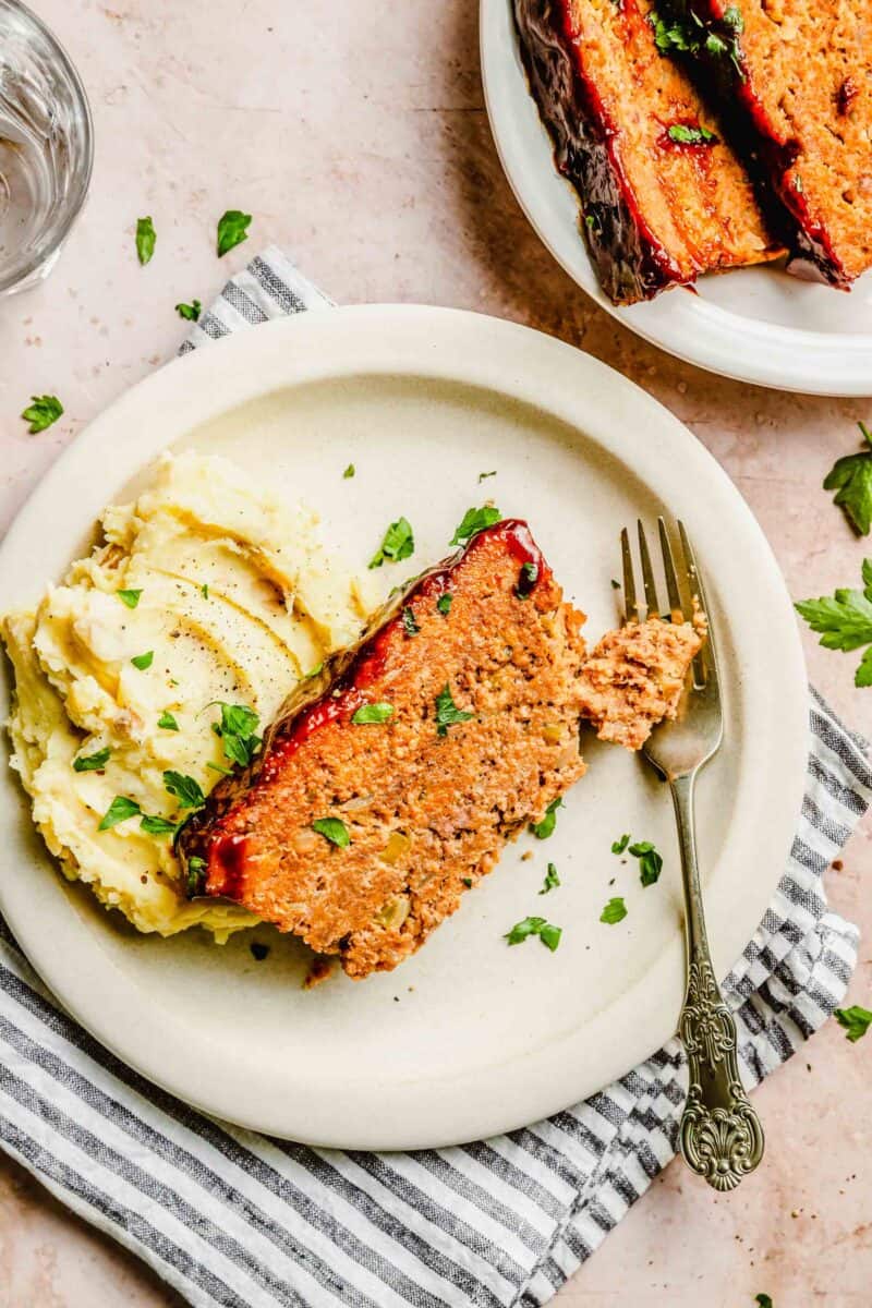 Slice of classic meatloaf on a plate with mashed potatoes.