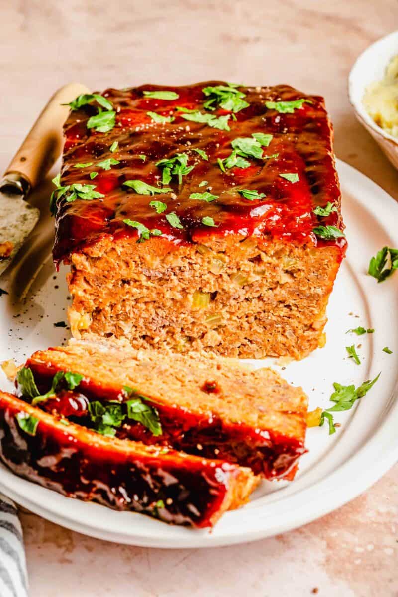 Sliced classic meatloaf on a plate with a knife.