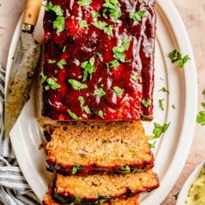 Sliced classic meatloaf on a plate with a knife.