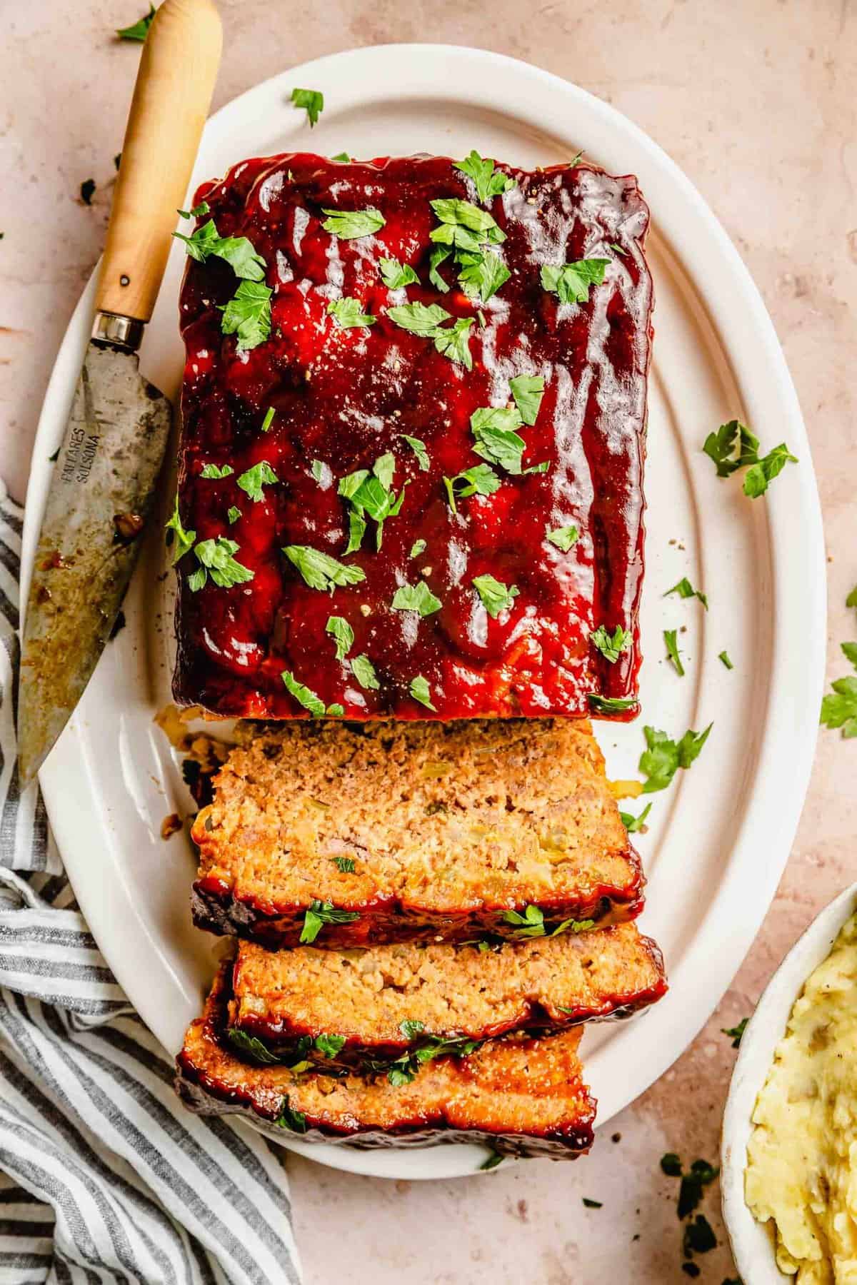 Sliced classic meatloaf on a plate with a knife.