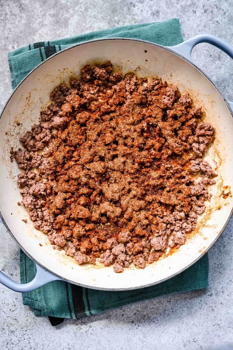 adding fajita seasoning to ground beef mixture in the cast iron skillet