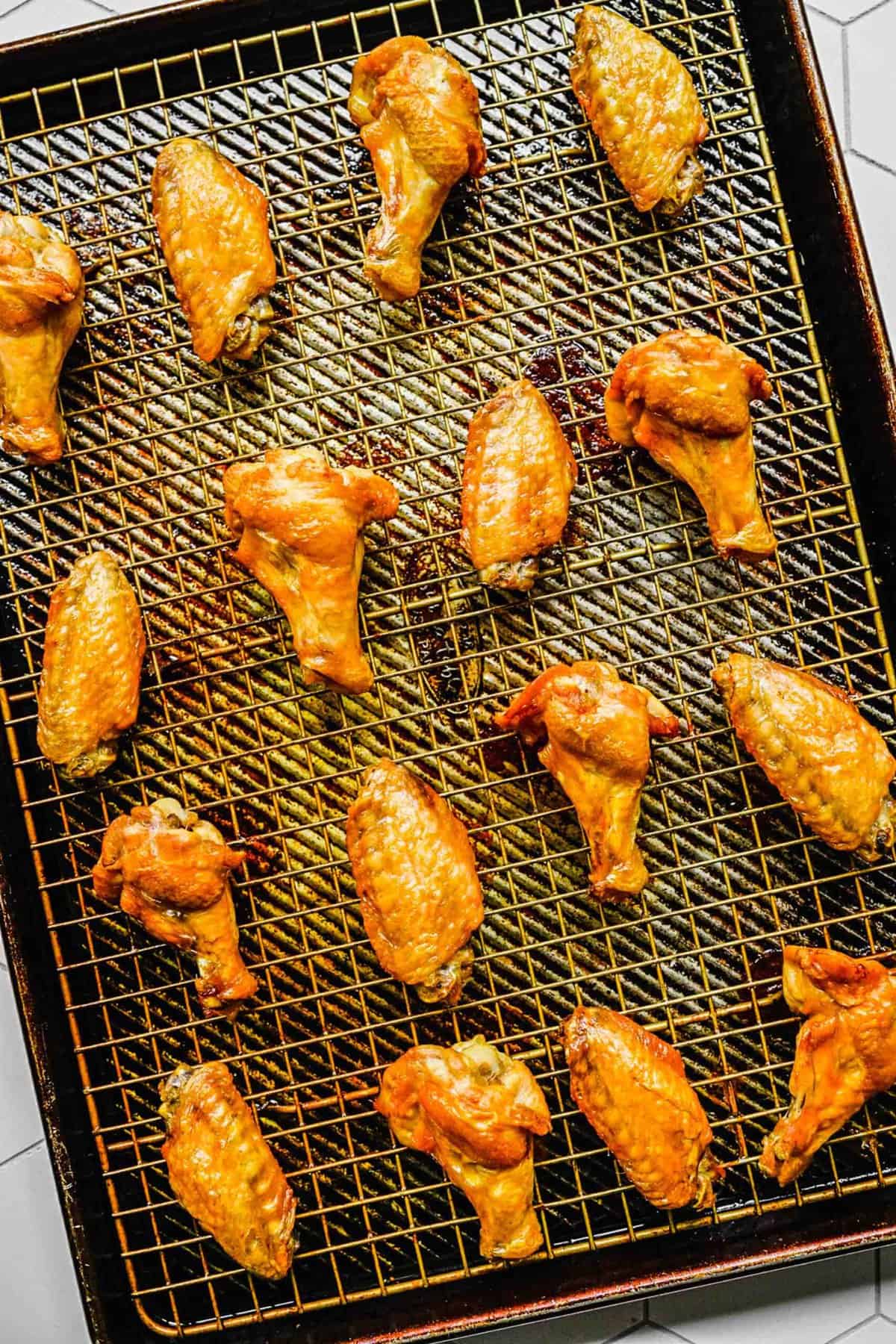 Lemon pepper chicken wings on a cooling wrack over a baking tray.