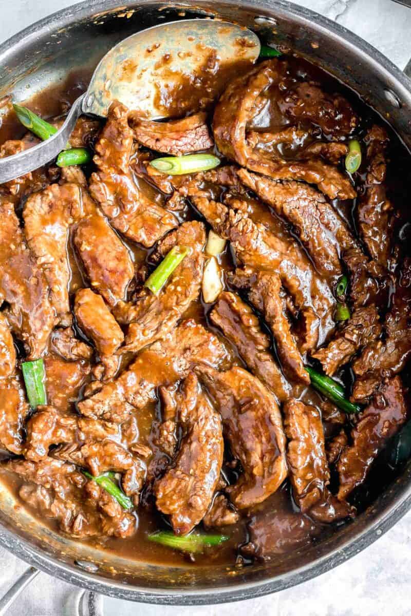 Mongolian beef finished in the pan with a spoon.