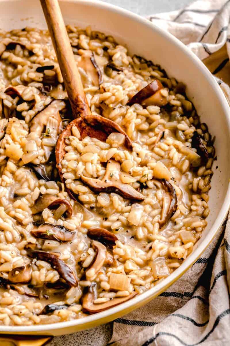 Stirring mushroom risotto with a wooden spoon.