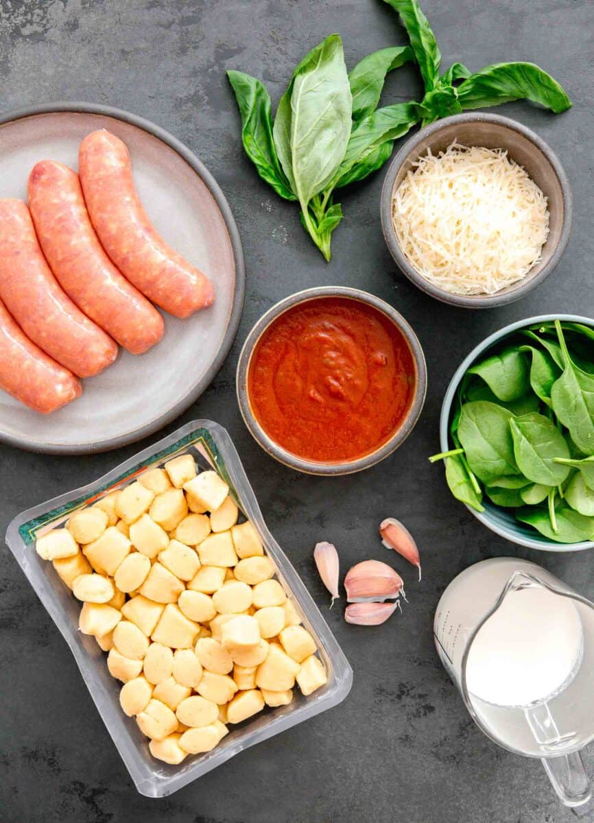 ingredients for one pan creamy chicken and gnocchi: italian chicken sausage, fresh basil, parmesan cheese, marinara sauce, baby spinach, garlic, heavy cream, and potato gnocchi