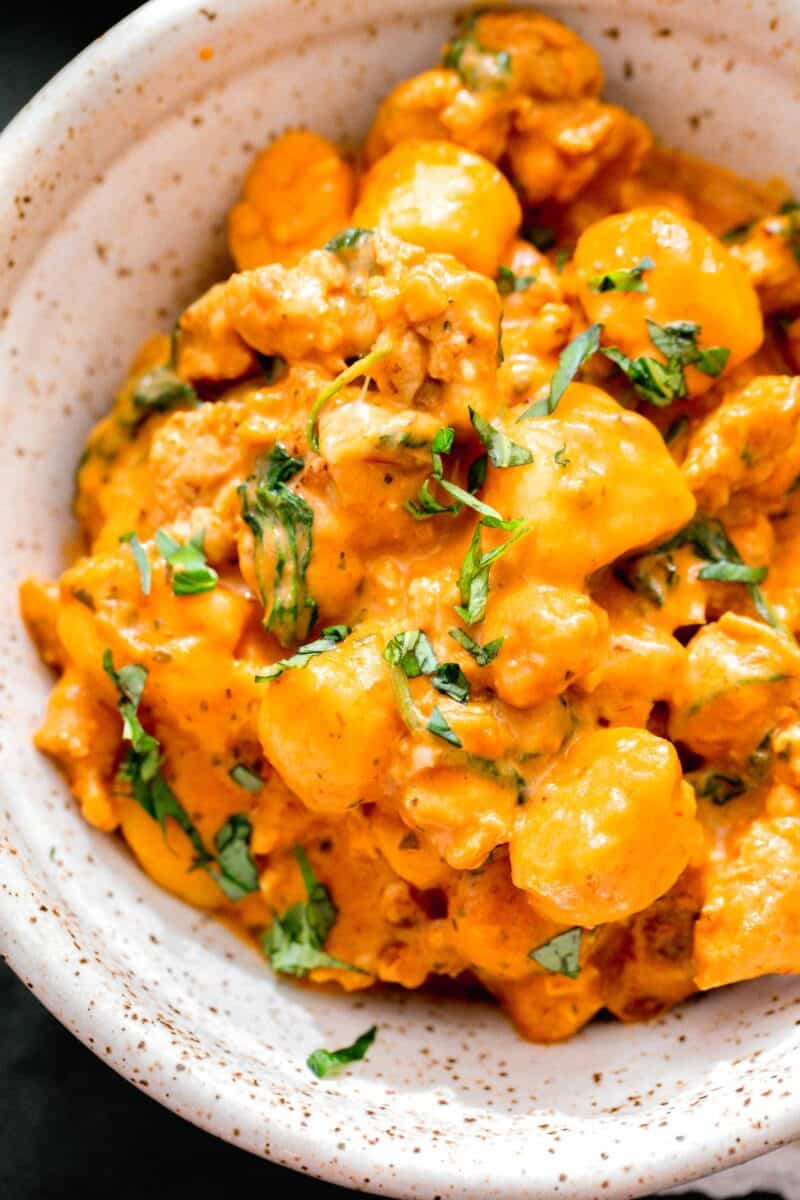 creamy chicken gnocchi in a ceramic speckled bowl with fresh basil sprinkled on top