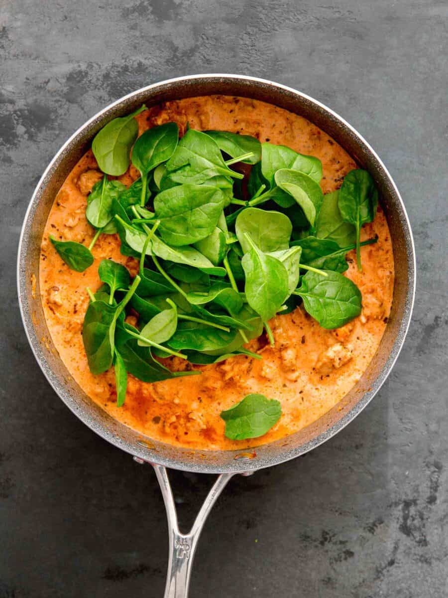 baby spinach leaves added to the skillet with the chicken sausage and sauce mixture