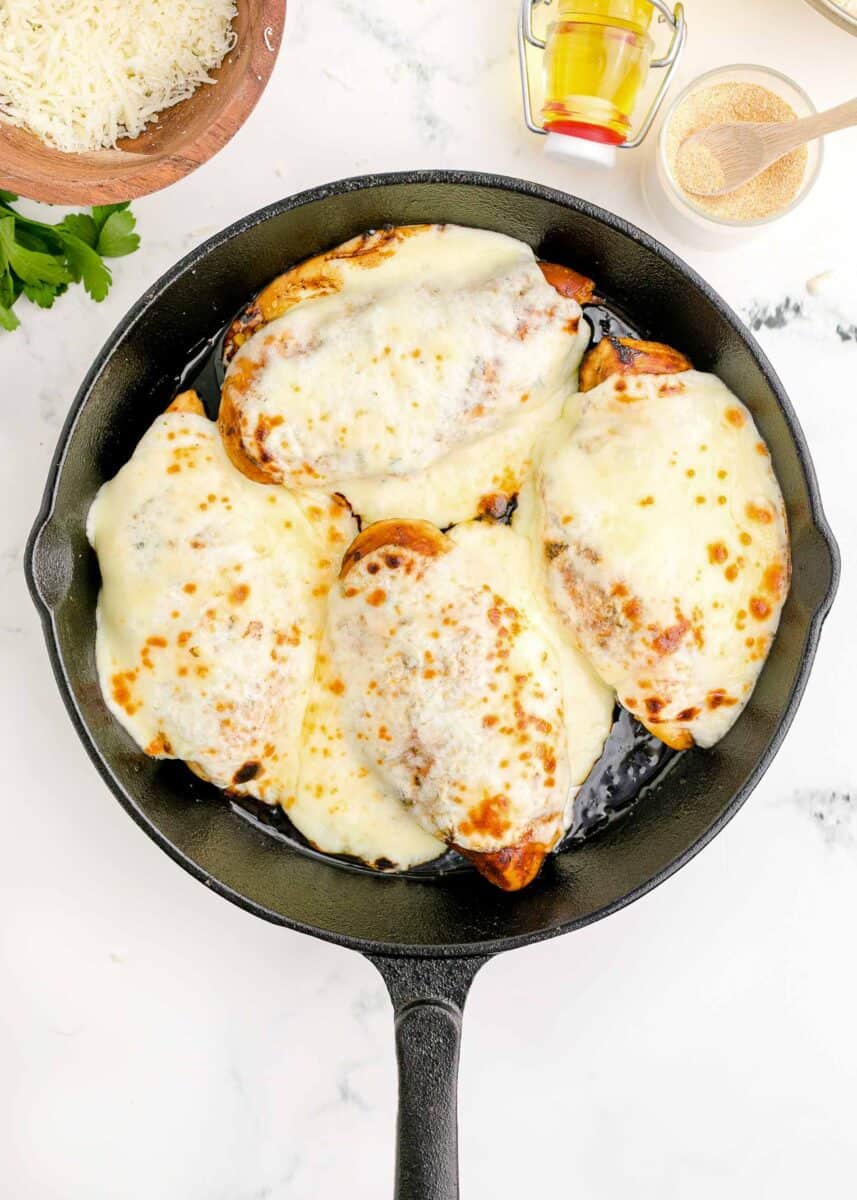 melted cheese on top of chicken breasts in cast iron skillet