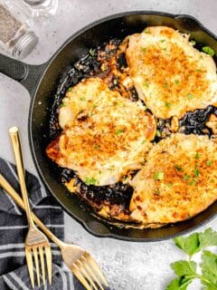 parmesan crusted chicken in cast iron skillet next to gold forks
