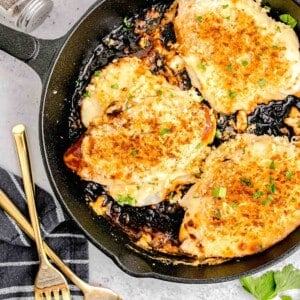 parmesan crusted chicken in cast iron skillet next to gold forks