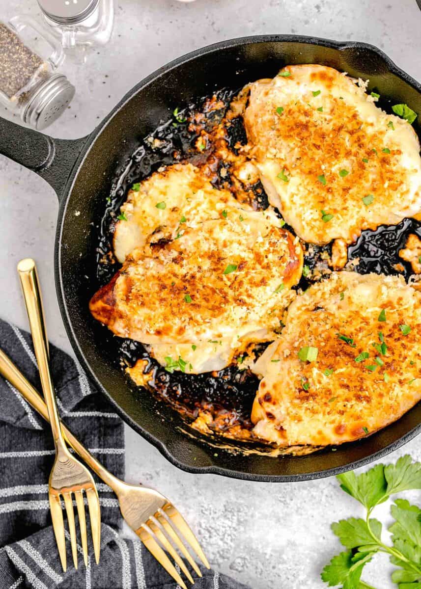 parmesan crusted chicken in cast iron skillet next to gold forks