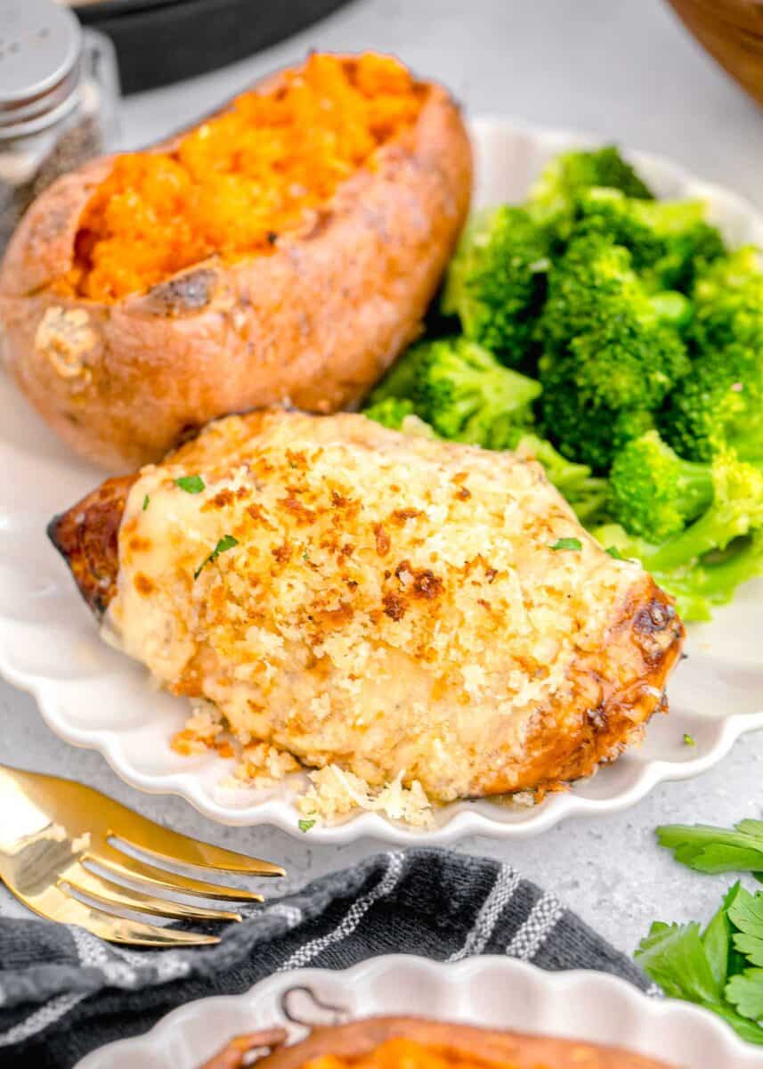 panko crusted chicken on a scalloped white plate with baked sweet potato and broccoli