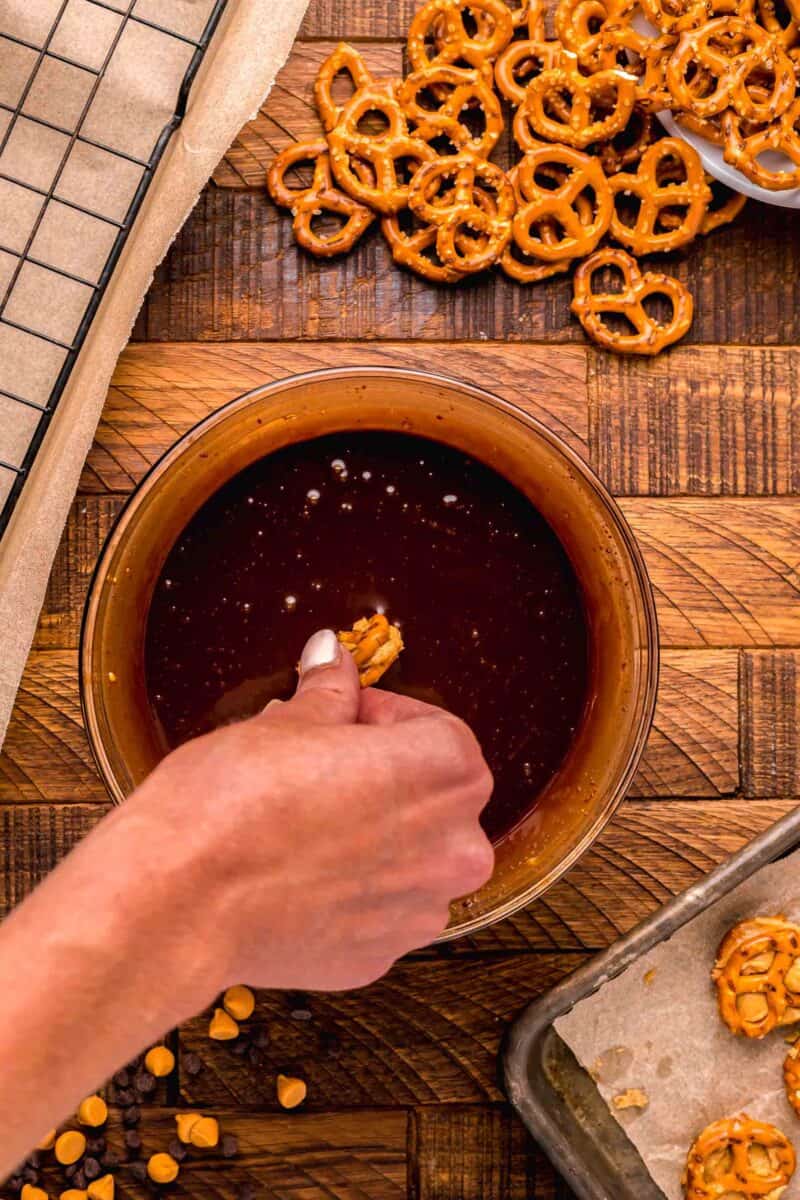 sandwiched peanut butter pretzel bites being dipped in melted chocolate