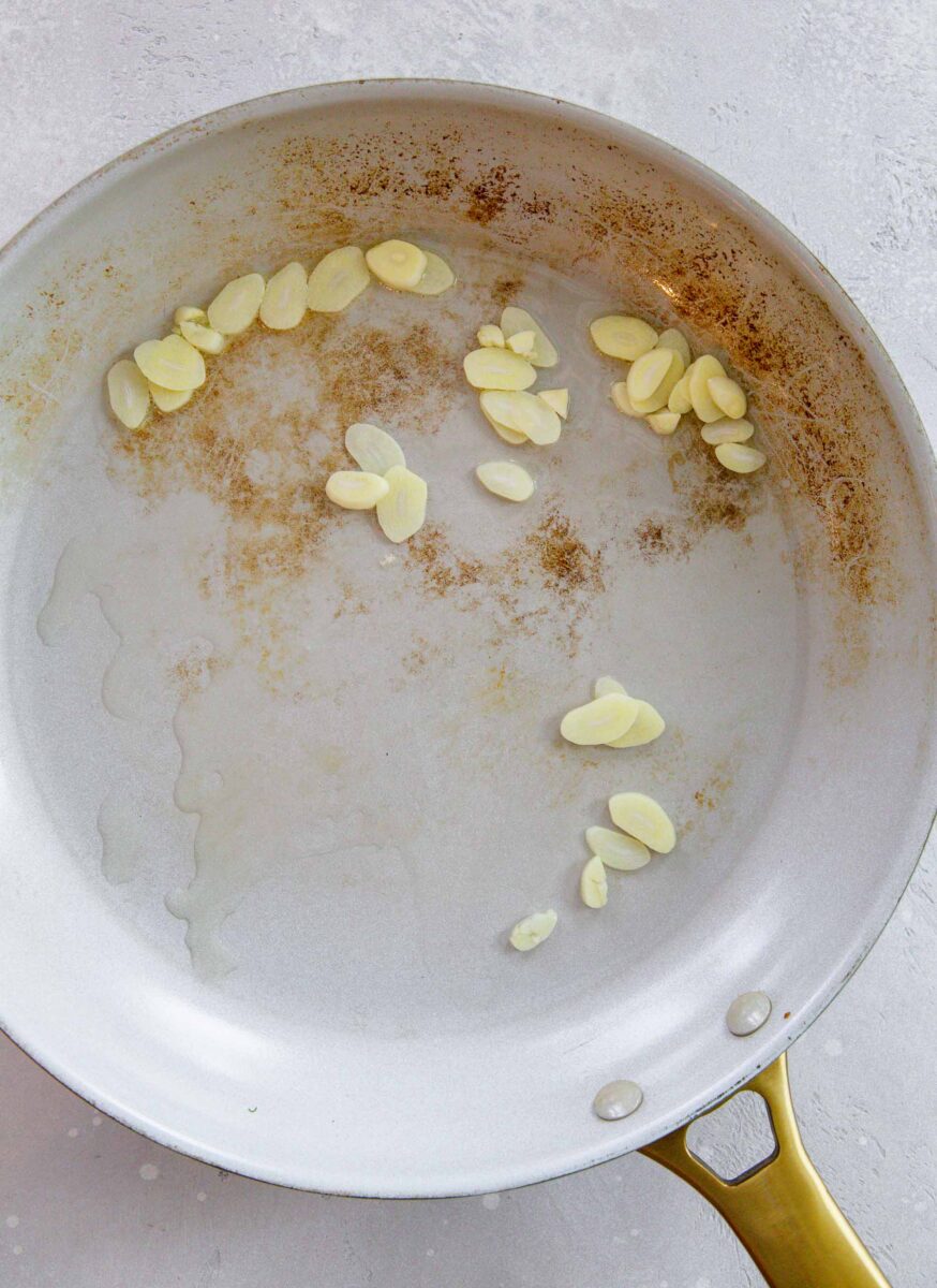 garlic slices sautéing in a skillet with oil