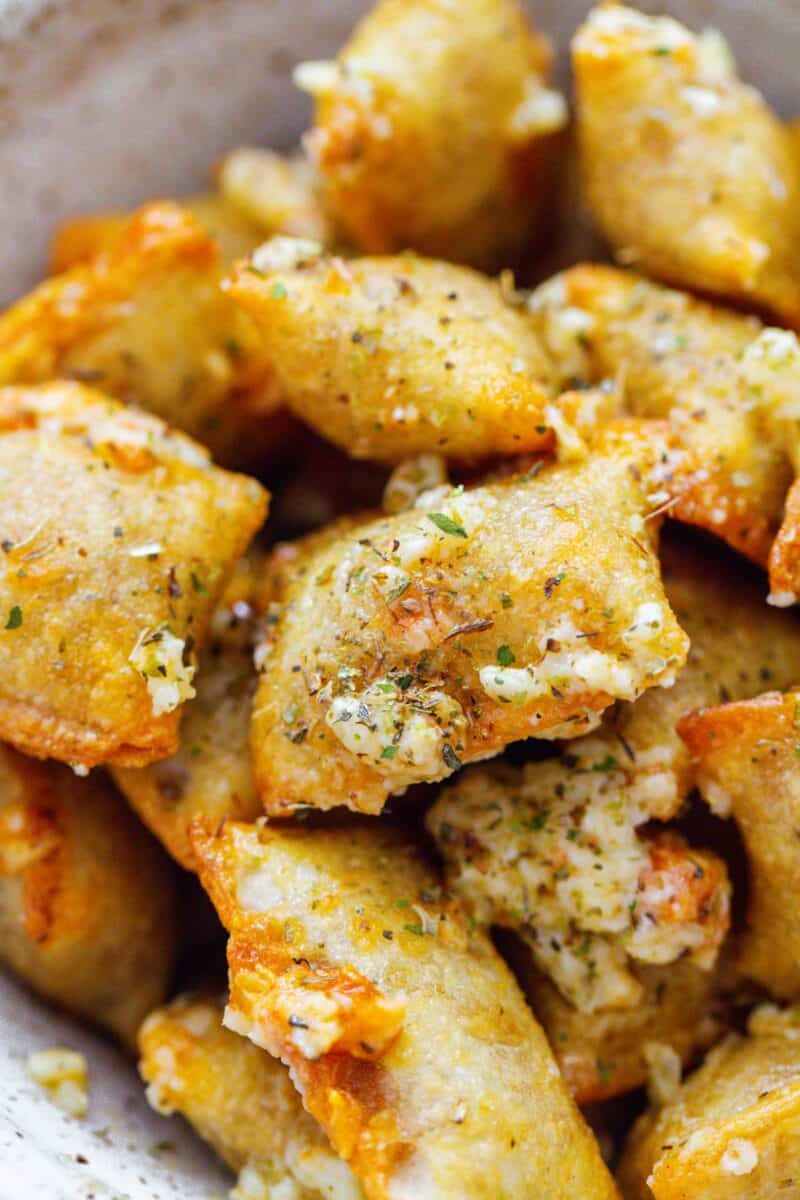 baked, golden brown pizza rolls with butter, garlic, and parmesan mixture on top with italian seasoning sprinkled