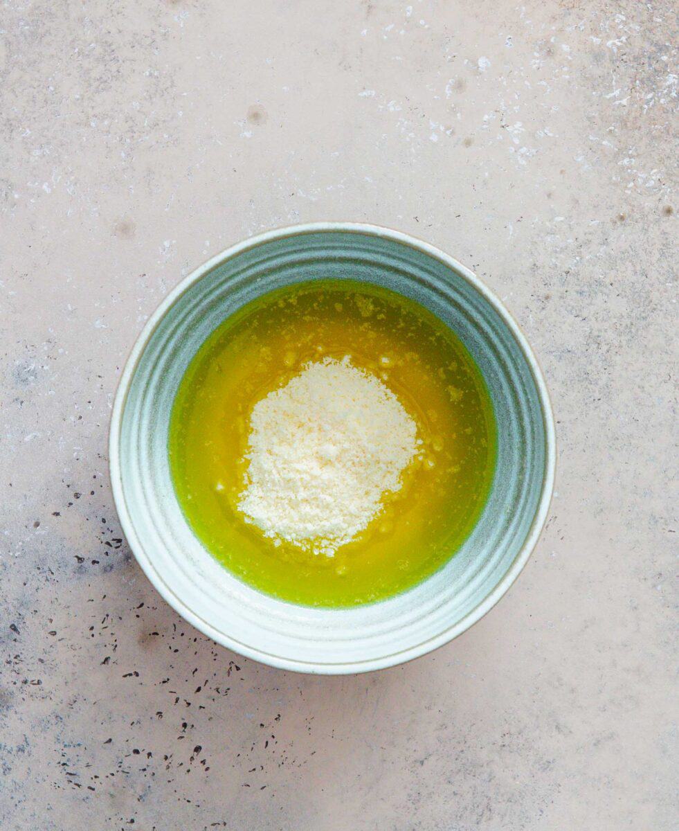 melted butter and parmesan cheese in a light blue ceramic bowl