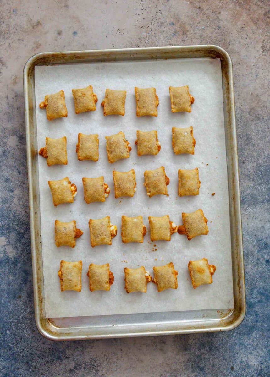 baked pizza rolls on a parchment paper lined rimmed baking sheet