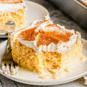 2 slices of tres leches cake on plates with a fork next to the cake pan.