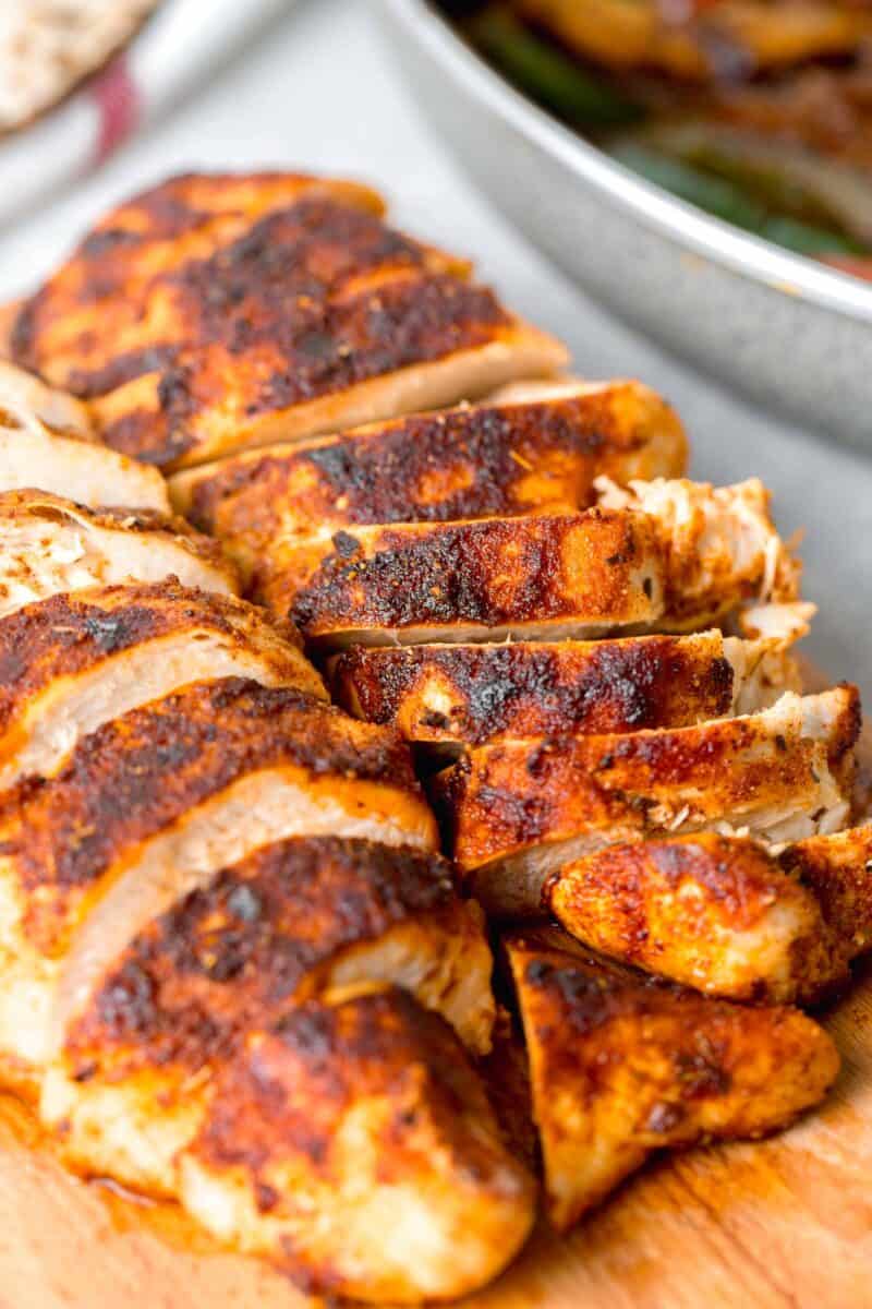 up close image of air fryer blackened chicken on a wooden cutting board to show blackened seasoning on chicken exterior
