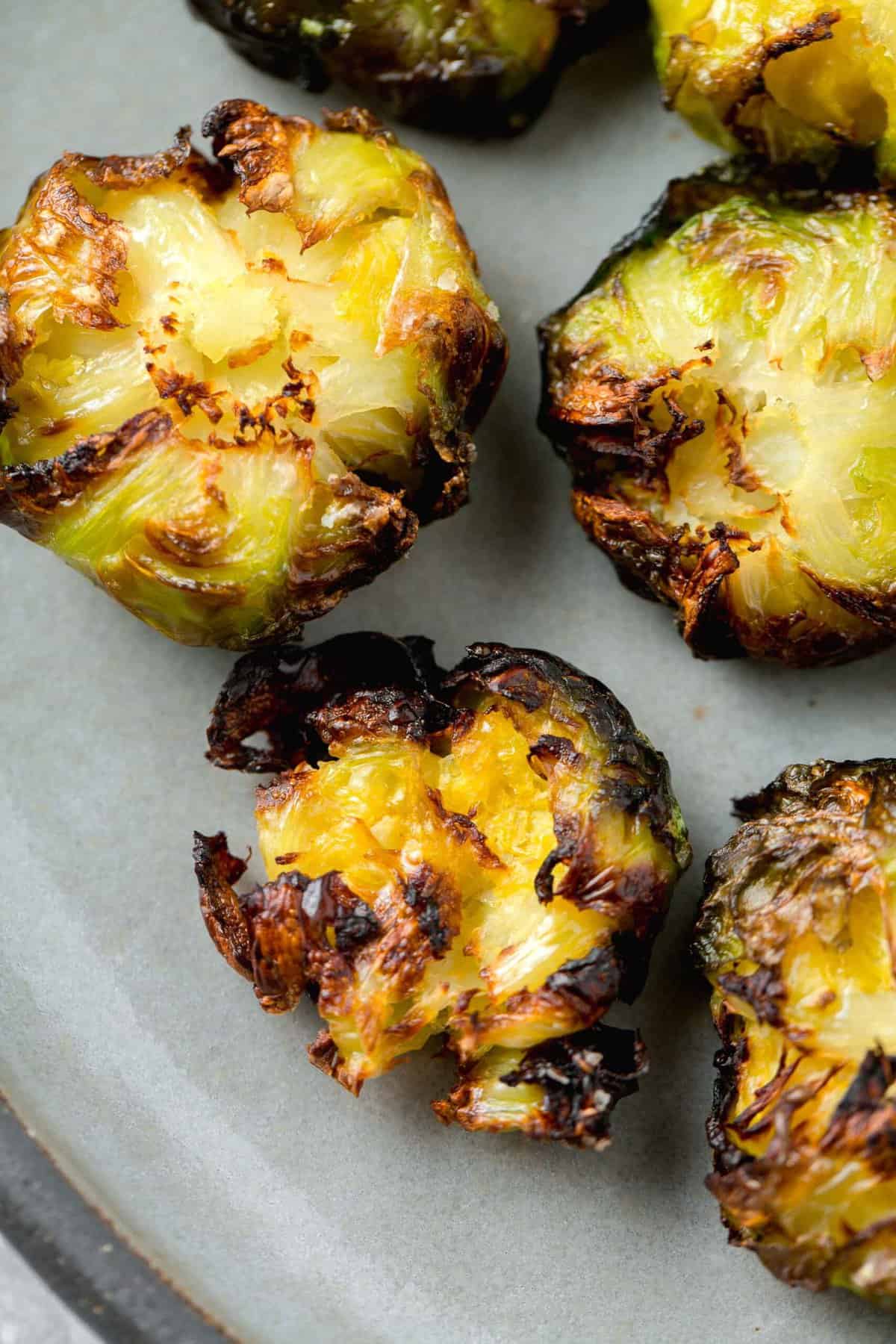 smashed brussels sprouts with crispy browned edges on a grey ceramic plate