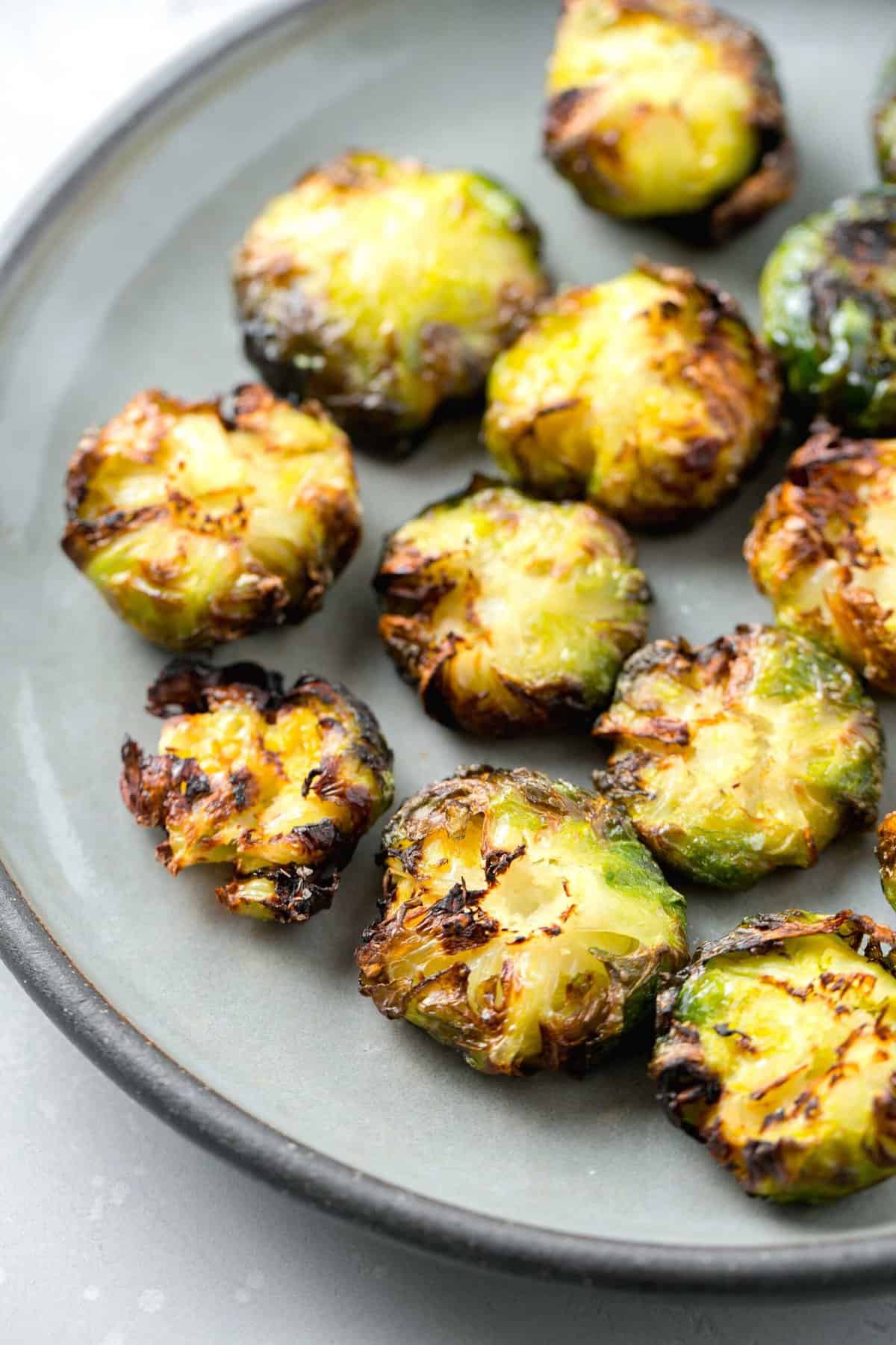 crispy and browned edged smashed brussels sprouts on a grey ceramic plate