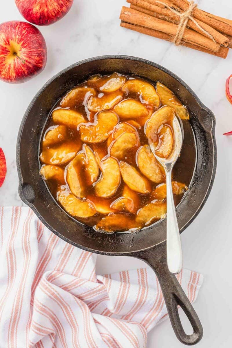 apple compote in a cast iron skillet with a silver spoon