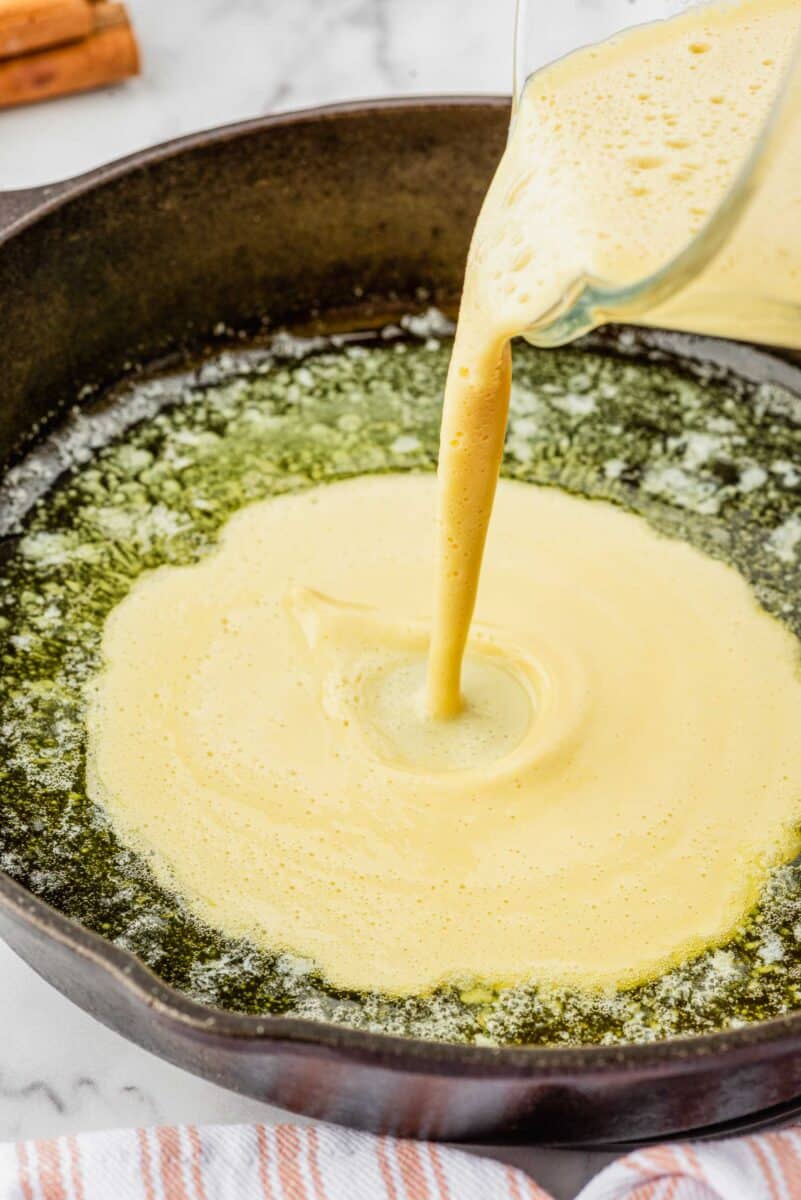 batter being poured into butter in the cast iron skillet