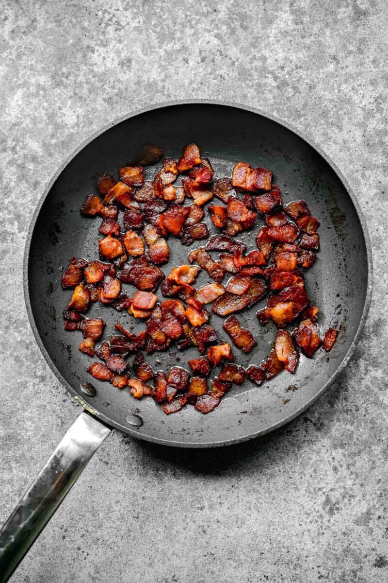 bacon being cooked and crisped up in a grey nonstick skillet