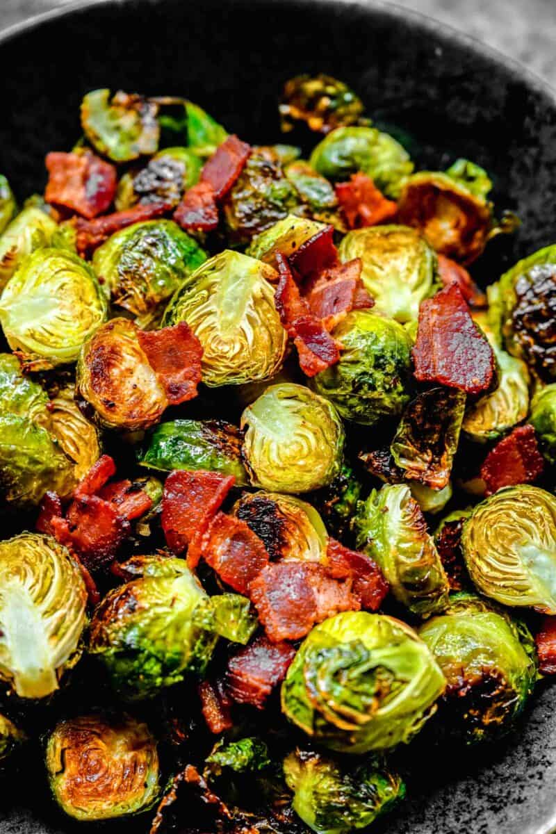roasted brussels sprouts and bacon in a ceramic black bowl