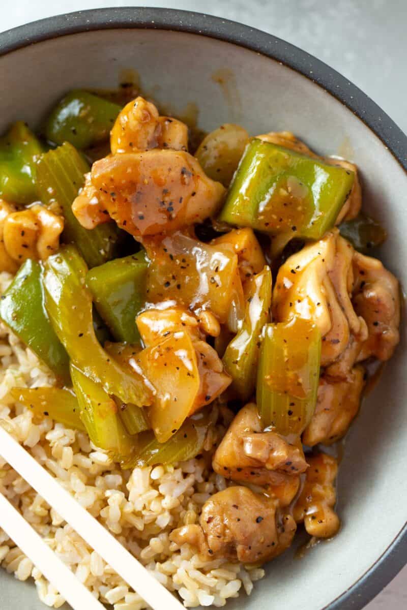 overhead image of black pepper chicken in a bowl with brown rice