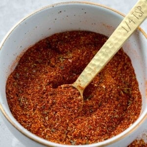 a bowl of blackening seasoning with a gold 1/4 teaspoon spoon inside next to blackening seasoning on the table